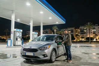 Station essence ouverte la nuit à Marseille avec un homme faisant le plein de sa voiture sous l'auvent illuminé